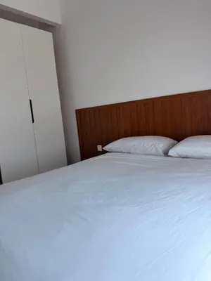 a bedroom with a white bed with a wooden headboard at Doksini in Simpang Ampat