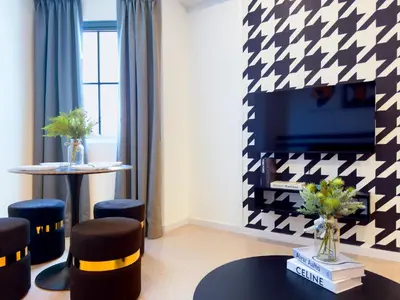 a living room with a tv and a table and stools at Stallionz Ipoh by ANGO in Ipoh