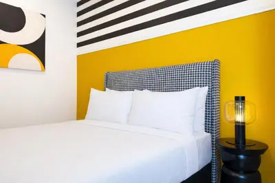 a bedroom with a white bed and a yellow wall at Stallionz Ipoh by ANGO in Ipoh