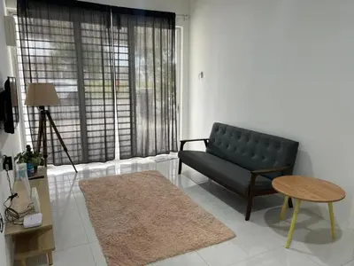 a living room with a black couch and a table at LAMAN SUZY Seri Iskandar in Seri Iskandar