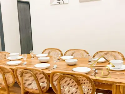 a wooden table with white plates and glasses on it at Ipoh Gunung Lang Mooncave Spacious 4BRHouse with 5 Queen Beds in Ipoh