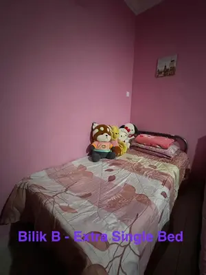 two stuffed animals sitting on a bed in a bedroom at RSyifaris ZH Homestay DSerai Wangi