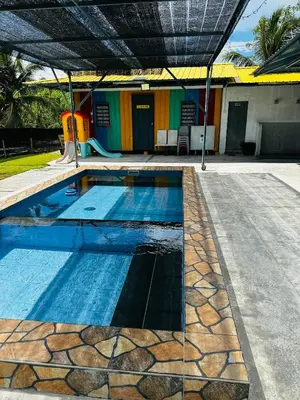 a swimming pool with a slide in front of a house at Teratak Kasih Kabinstay in Tanjung Karang