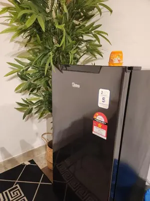 a black refrigerator with stickers on it next to a plant at Sun Pista Home by Ipoh Maju Stay in Ipoh