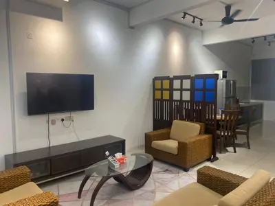 a living room with a tv and chairs and a table at Sentosa Grand Homestay in Kulim