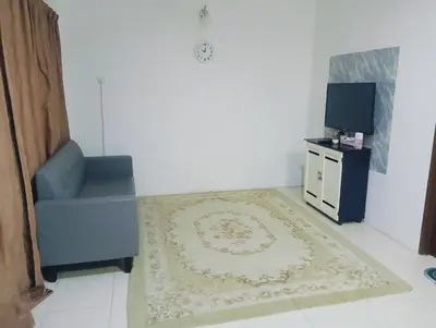 a living room with a chair and a television at Room Stay YNS Kampar Putra 1 Bilik dan Bilik Air in Kampar