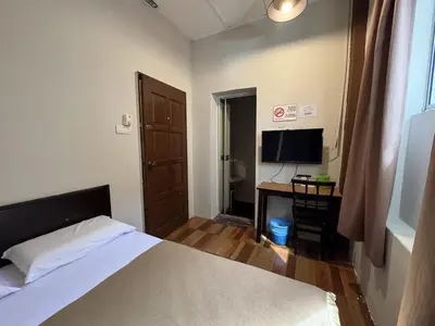 a bedroom with a bed and a desk with a television at Hotel London Kuala Lipis in Kuala Lipis