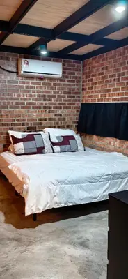 a bed in a room with a brick wall at Sekinchan Tiny House in Sekincan
