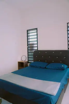 a bed with blue sheets and blue pillows in a room at Wewe Homestay CL2 in Kampung Gajah