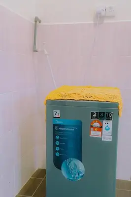 a washing machine in a bathroom with a faucet at Wewe Homestay CL2 in Kampung Gajah