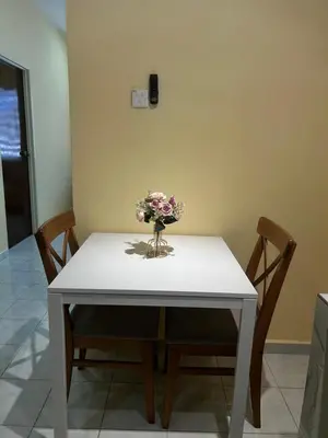 a white table with a vase of flowers on it at Homestay D'Kampong in Teluk Intan