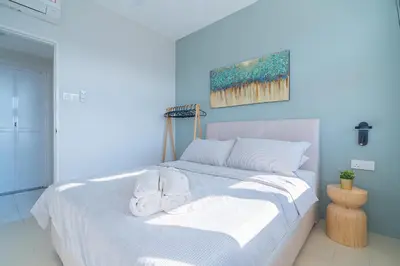 a white bed with two white towels on top of it at Stylish 3BR Stay Near Gurney Drive Free Parking in George Town