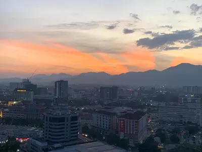a city skyline at sunset with mountains in the background at Piccadilly Greentown by Jun Residence in Ipoh