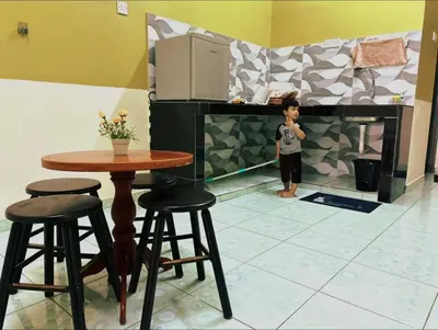 a young boy standing in a kitchen with a table and stools at Wawa Homestay Ipoh in Ipoh