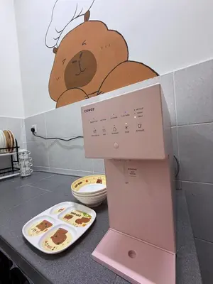 a kitchen counter with a clock with a teddy bear on the wall at Pantai Remis Capybara House in Pantai Remis