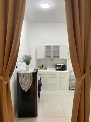 a kitchen with white cabinets and a table with curtains at NN Homestay Tasek Gelugor in Kampong Selamat
