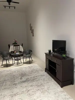 a living room with a tv and a table with chairs at NN Homestay Tasek Gelugor in Kampong Selamat