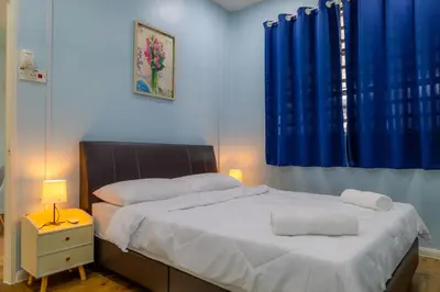 a bedroom with a large bed with blue curtains at Adno Homestay Batu Kawan 2QB1SB in Simpang Ampat