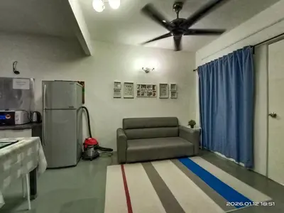 a living room with a chair and a refrigerator at Adno Homestay Batu Kawan 5SB in Simpang Ampat