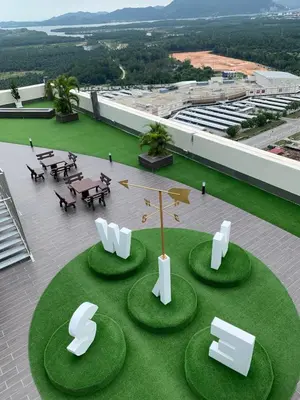 a building with a circle of grass with tables and chairs at B-Ulike-HomeStay-3Room-TheVenus in Sitiawan