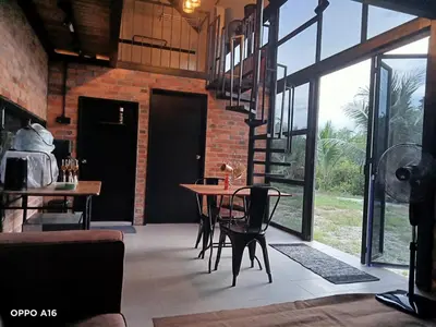 a dining room with a table and chairs and windows at Tepian Sawah Semanggol in Simpang Ampat Semanggol
