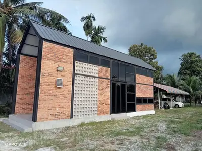 a brick building with a garage at Tepian Sawah Semanggol in Simpang Ampat Semanggol