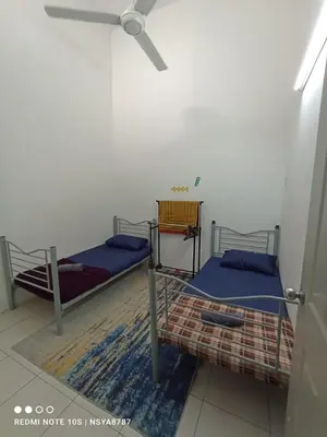 two beds in a room with a ceiling fan at De Ariffa Homestay مسلم in Lahat