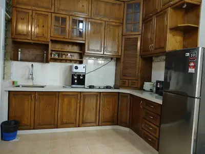 a kitchen with wooden cabinets and a stainless steel refrigerator at Warmy 4 Bedrooms Double Storey Homestay, Few mins to Town, by MR HOMESTAY in Teluk Intan
