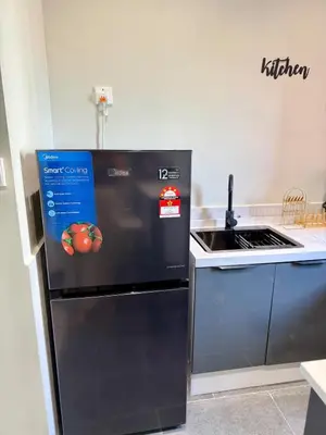 a black refrigerator in a kitchen next to a stove at Piccadilly Ipoh by Iconique in Ipoh