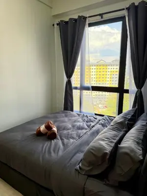 a teddy bear laying on a bed with a window at Piccadilly Ipoh by Iconique in Ipoh