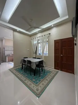 a dining room with a table and chairs on a rug at Teratak Bonda in Temuh