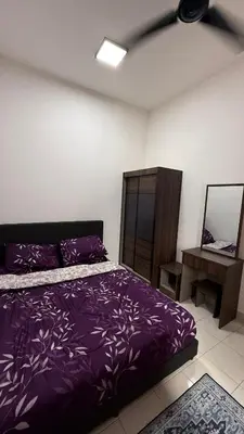 a bedroom with a purple bed and a table at Homestay Azizi in Seri Iskandar