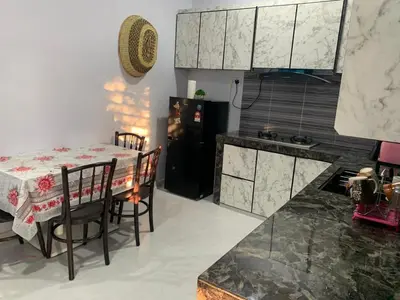 a kitchen with a table and a black refrigerator at Homestay D'Kutan Bandar Baharu Kedah in Bandar Baharu