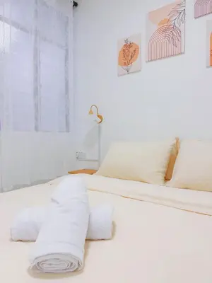 a white bed with white sheets and towels on it at Cozy Homestay 6-10pax Double storey in Bukit Mertajam