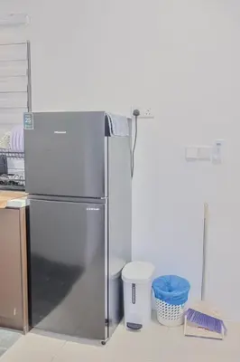 a stainless steel refrigerator in a kitchen with two trash cans at Picaddily Suites by Homexa Hospitality in Ipoh