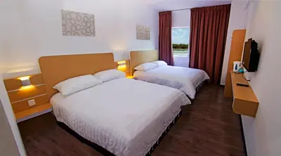 a hotel room with two beds and a television at Thanks Hotel in Parit Buntar