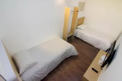 a small room with two beds and a desk at Thanks Hotel in Parit Buntar