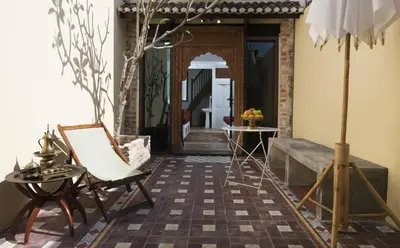 a room with a chair and a table and a mirror at Jawi Peranakan Mansion in George Town