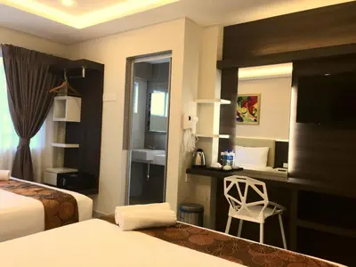 a hotel room with a bedroom with two beds and a chair at Louis Hotel in Taiping