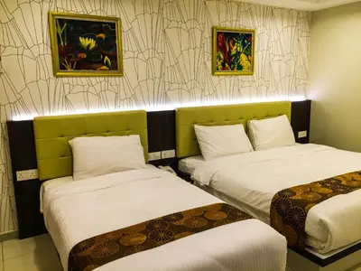 a hotel room with two beds and paintings on the wall at Louis Hotel in Taiping