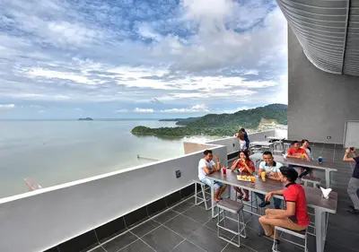 a group of people sitting at a table on a balcony overlooking the water at Lexis Suites Penang in Bayan Lepas
