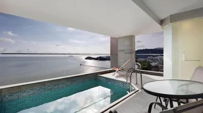 a balcony with a swimming pool and a table with a view at Lexis Suites Penang in Bayan Lepas