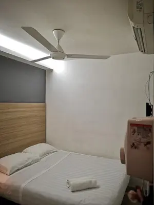 a bedroom with a bed with a ceiling fan at Dragon Door Hotel in Sitiawan