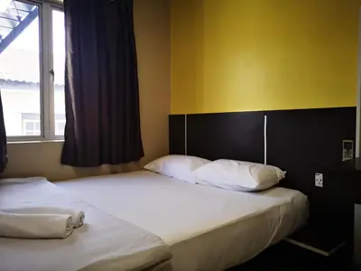 two beds in a bedroom with a yellow wall at Dragon Door Hotel in Sitiawan