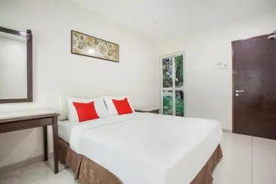 a bedroom with a large white bed with red pillows at Sam Hotel Sitiawan in Sitiawan