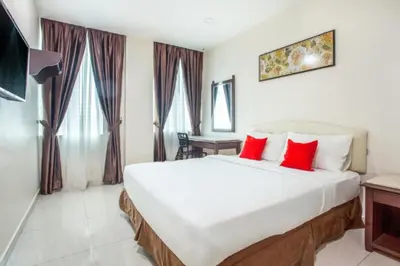 a bedroom with a large white bed with red pillows at Sam Hotel Sitiawan in Sitiawan