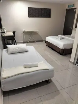 a room with two beds and a table at Sam Hotel Sitiawan in Sitiawan