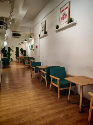 a restaurant with wooden tables and green chairs at Sam Hotel Sitiawan in Sitiawan
