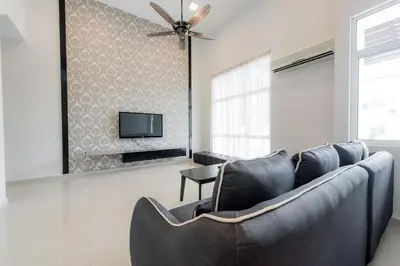 a living room with a couch and a tv at New Shamrock Beach Villas Seaview in Batu Ferringhi