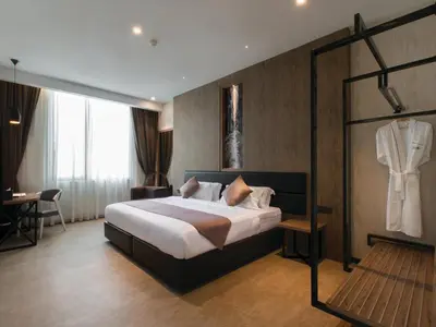 a hotel room with a bed and a suit hanging on a wall at Iconic Hotel in Bukit Mertajam